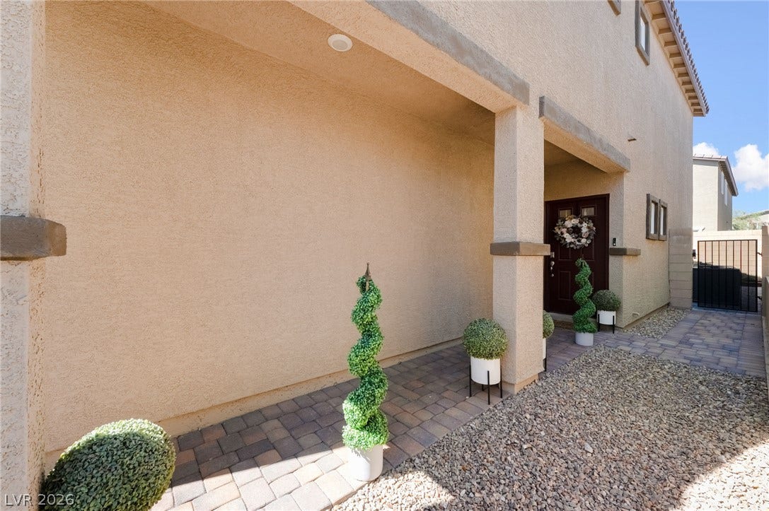 10958 Cheshire Woods Avenue, Las Vegas, NV 89166 A welcoming stucco walkway with paved flooring leads directly to the covered main entrance.