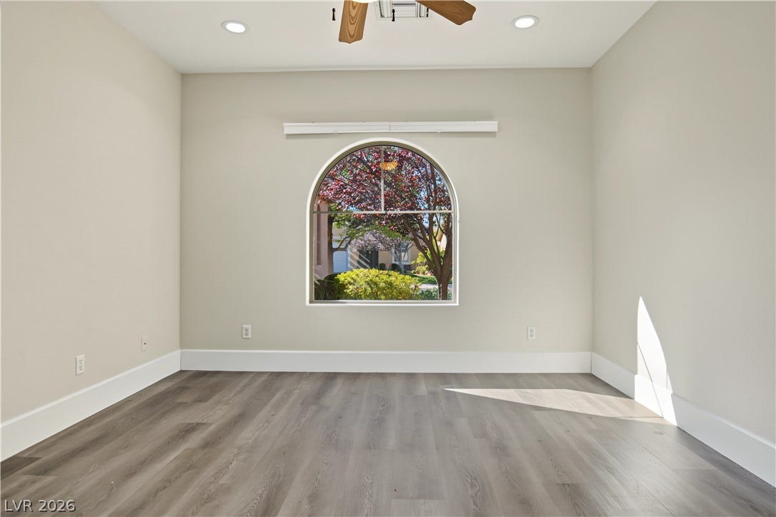 6 Mohansic Road, Henderson, NV 89052 An arched window frames serene outdoor views in this versatile space featuring durable wood-look flooring.