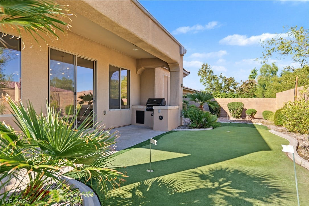 6 Mohansic Road, Henderson, NV 89052 An inviting covered patio overlooks a private putting green under clear blue skies.