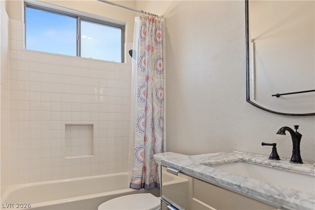 6 Mohansic Road, Henderson, NV 89052 A classic tiled shower and tub setup stands adjacent to a marble-topped vanity.