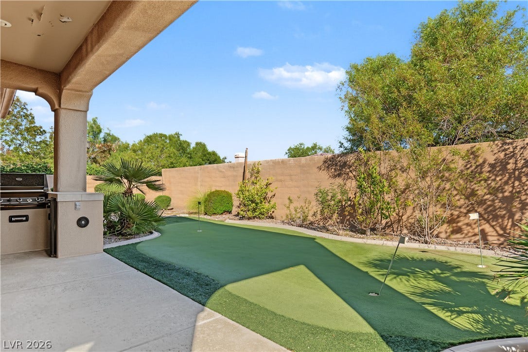 6 Mohansic Road, Henderson, NV 89052 A private putting green sits nestled against a concrete patio under clear desert skies.