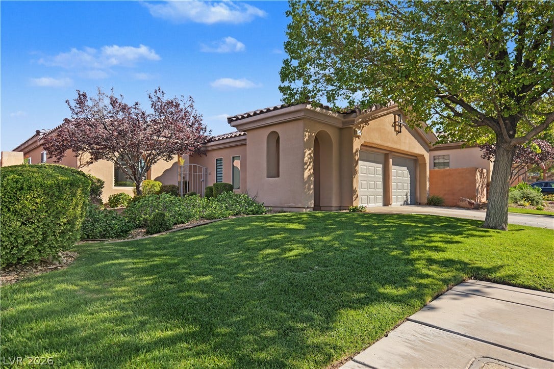 6 Mohansic Road, Henderson, NV 89052 Mature trees shade a manicured lawn leading toward this southwestern-style stucco home.