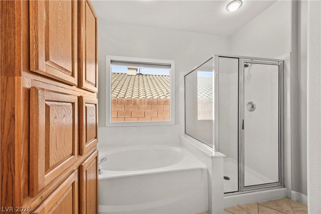 753 Wigan Pier Drive, Henderson, NV 89002 Natural light pours over a built-in soaking tub alongside a glass-enclosed walk-in shower.