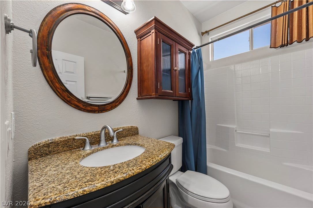 753 Wigan Pier Drive, Henderson, NV 89002 A polished stone vanity and classic tiled tub shower highlight this tidy bathroom.