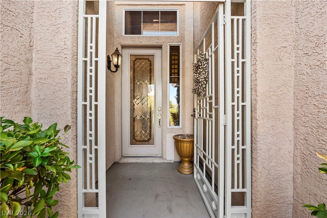 753 Wigan Pier Drive, Henderson, NV 89002 An inviting gated entry features a decorative glass front door set against a stucco exterior.