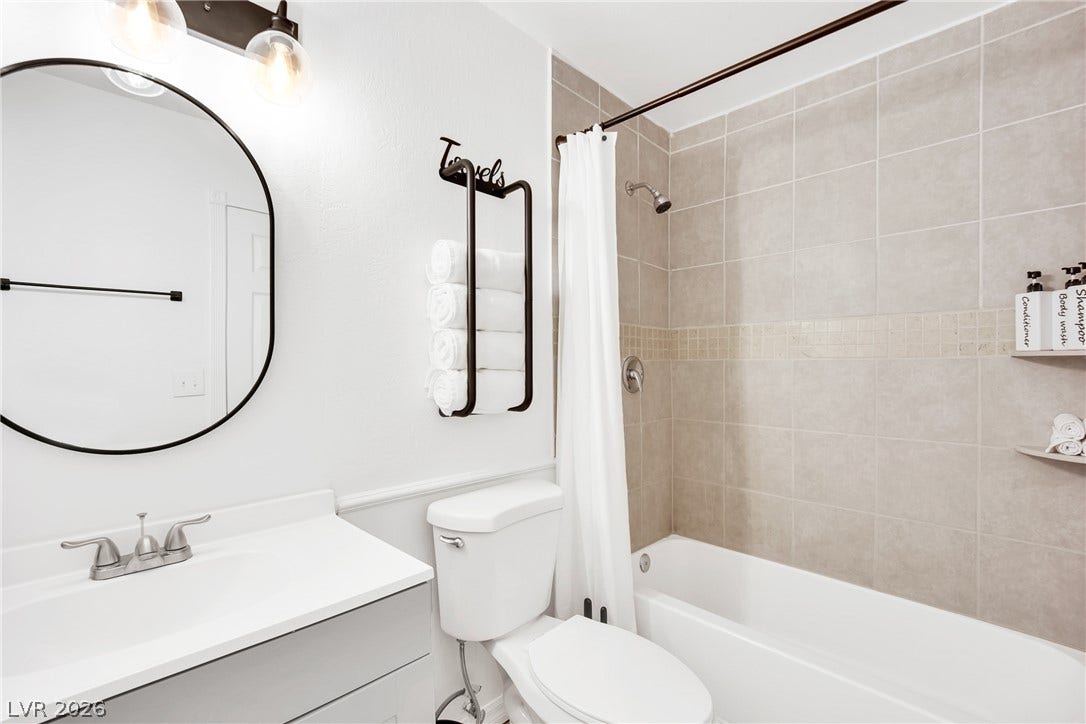 Tiled tub surround meets modern vanity in this clean bathroom layout.
