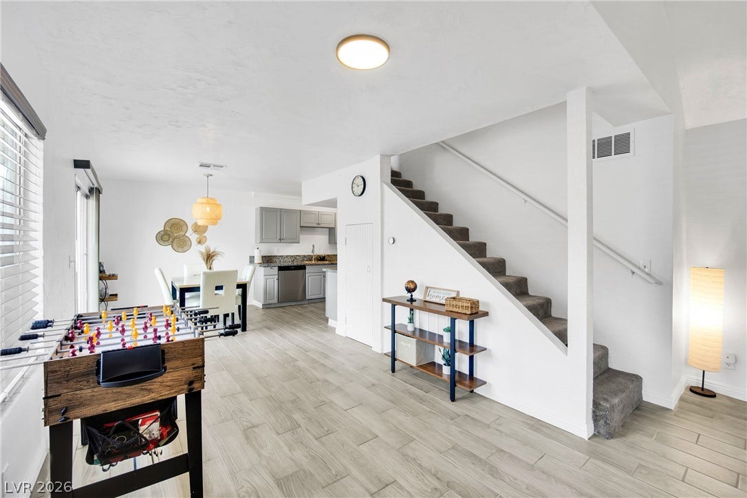An open layout connects the dining space and kitchen on wood-look tile flooring.