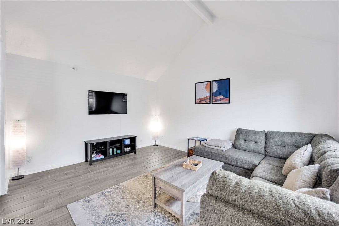 Vaulted ceilings soar over durable wood-look tile flooring in this inviting living space.