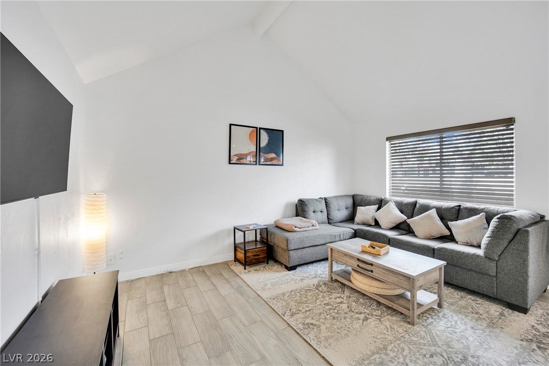 Soaring vaulted ceilings and durable wood-look tile flooring define this welcoming living space.