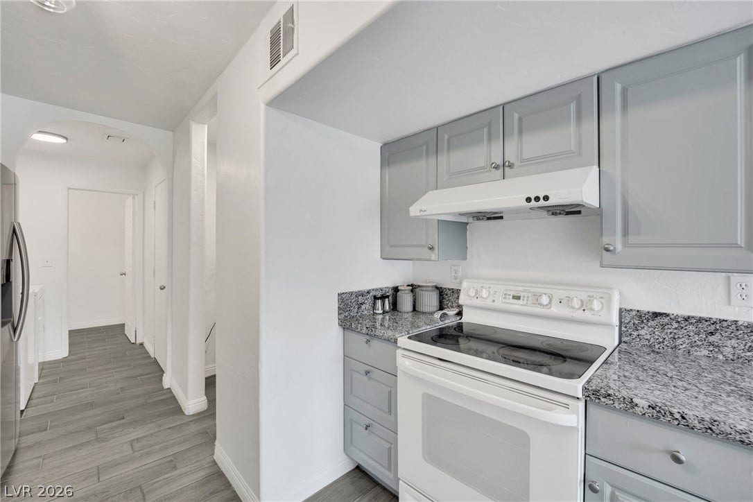 Granite countertops and clean cabinetry flank a modern range in this updated kitchen area.