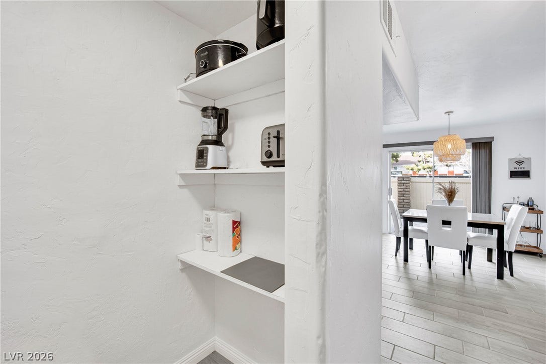 An open floorplan connects the built-in pantry shelving to a bright dining space.