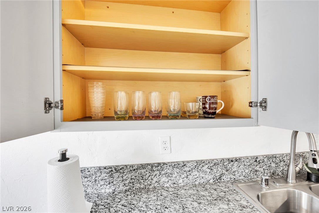 Sturdy built-in cabinets offer organized storage above granite countertops and a stainless steel sink.