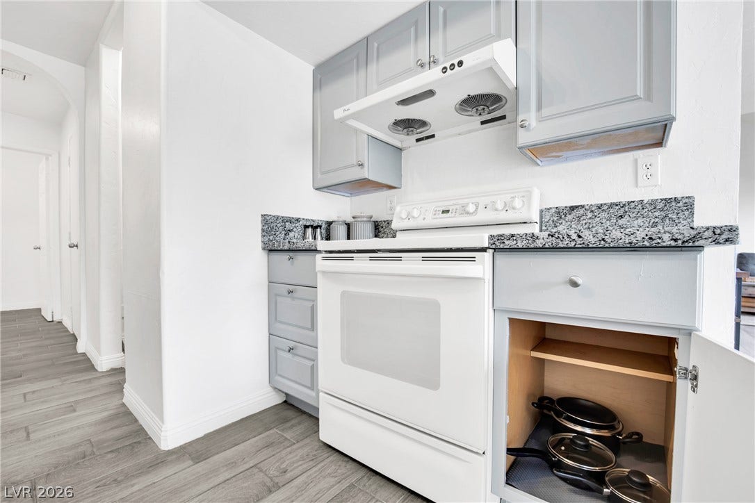 Granite countertops and clean cabinetry frame a white range in this updated culinary space.