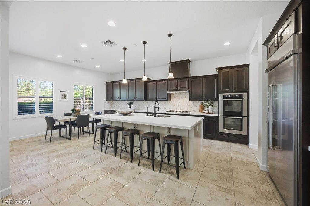 8030 Palm Cove Court, Las Vegas, NV 89129 Rich dark cabinetry contrasts beautifully with a massive light stone island and tiled flooring.