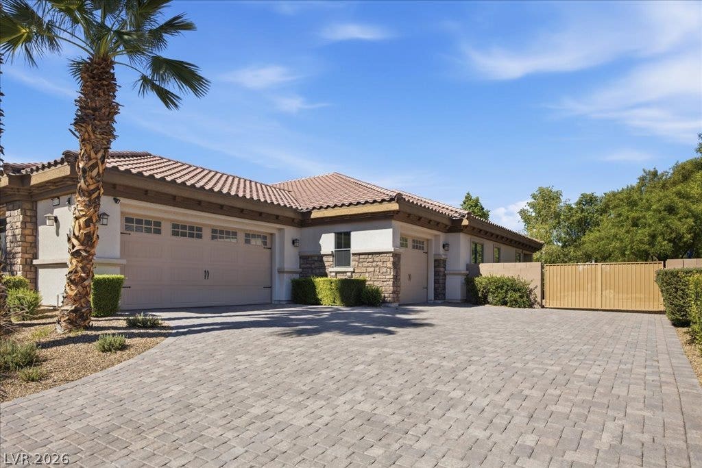 8030 Palm Cove Court, Las Vegas, NV 89129 An expansive paver driveway leads to a classic tile-roofed exterior under clear blue skies.