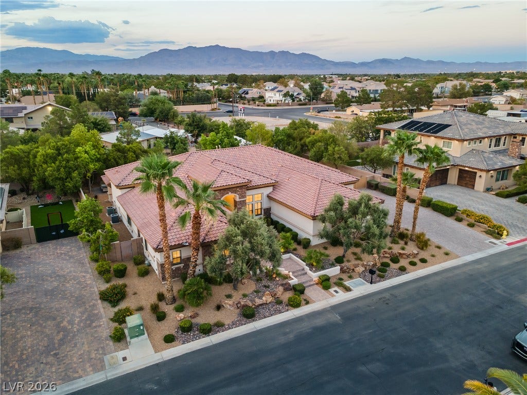8030 Palm Cove Court, Las Vegas, NV 89129 An aerial perspective showcases a tile-roofed home nestled against a backdrop of distant mountains.