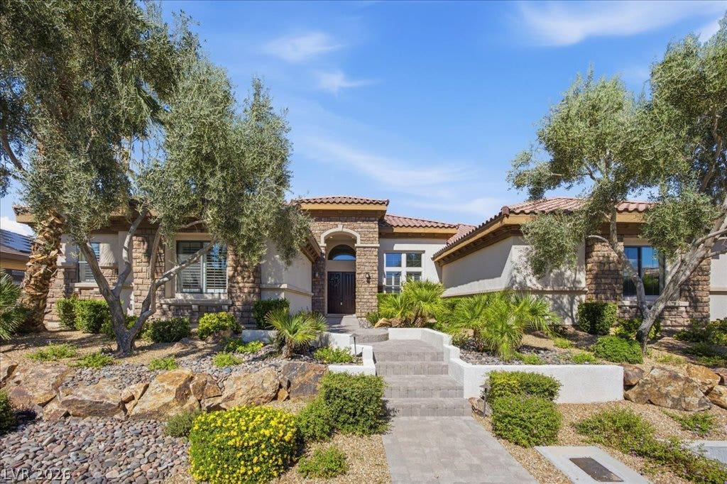 8030 Palm Cove Court, Las Vegas, NV 89129 Artfully terraced stone pathways and native desert plantings frame a grand stone-accented entryway.