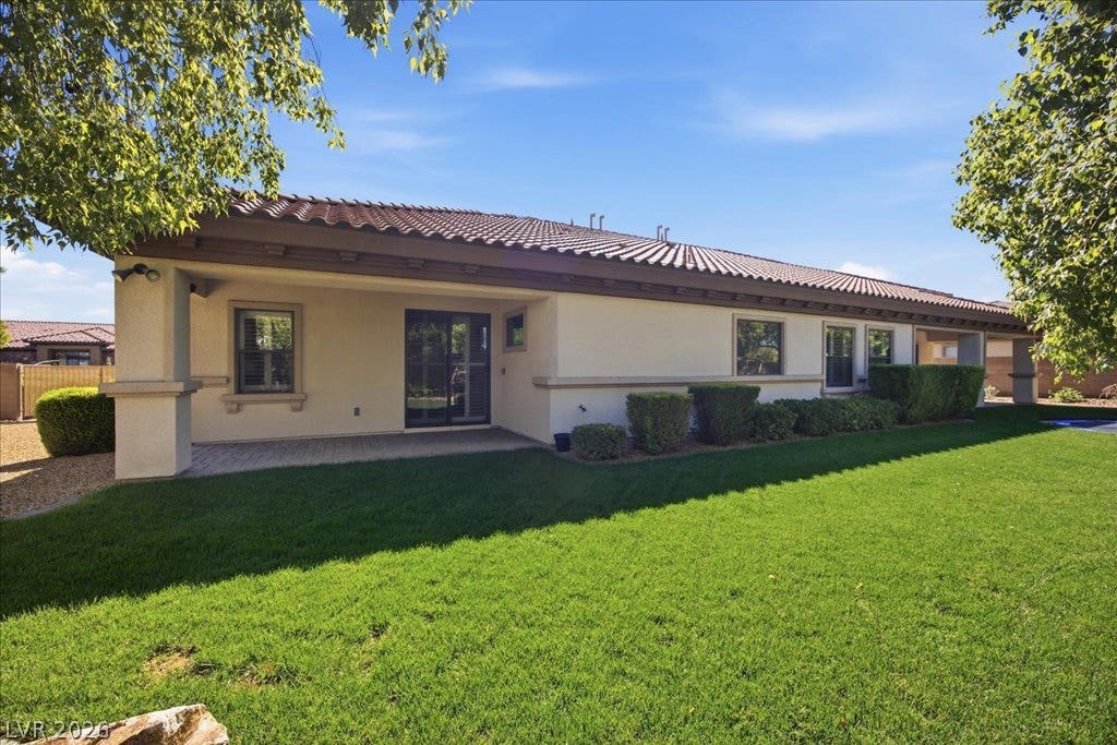 8030 Palm Cove Court, Las Vegas, NV 89129 A deep covered back patio overlooks a manicured green lawn framed by mature trees.