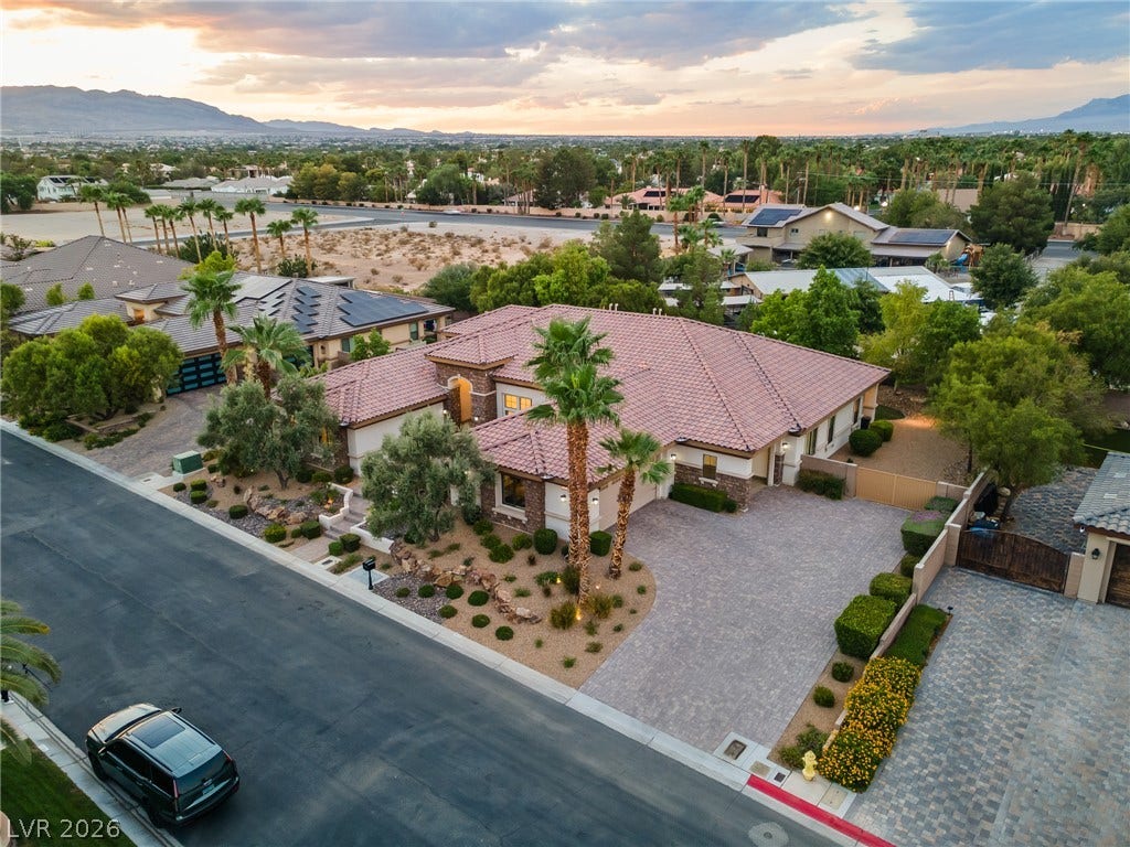 8030 Palm Cove Court, Las Vegas, NV 89129 Desert landscaping and a paved driveway complement this elegant tile-roofed home under a warm twilight sky.