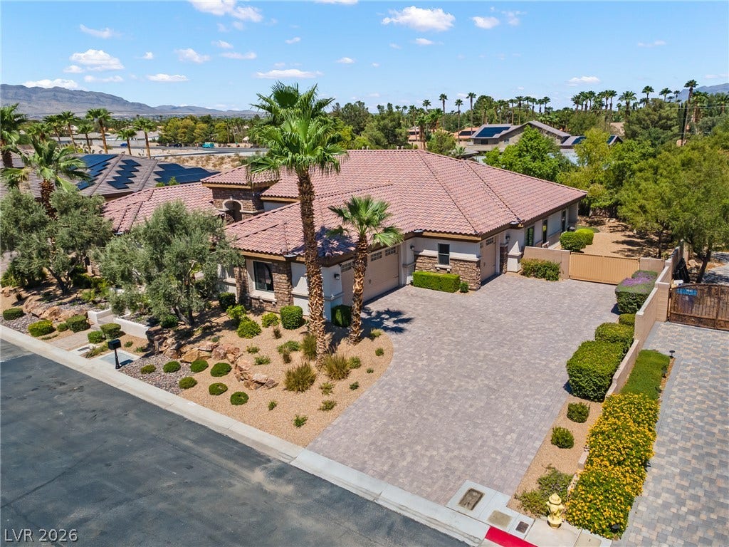 8030 Palm Cove Court, Las Vegas, NV 89129 An expansive paver driveway leads to a classic tile-roof home framed by majestic palm trees.