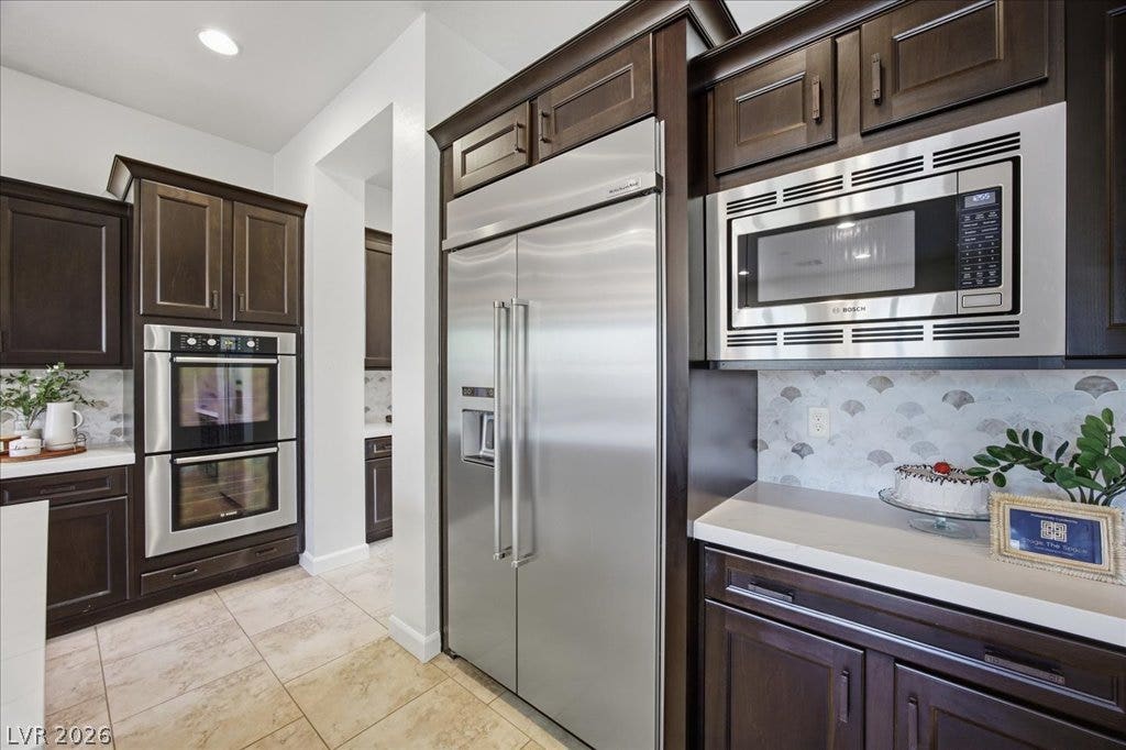 8030 Palm Cove Court, Las Vegas, NV 89129 Rich dark wood cabinets surround high-end stainless steel appliances and elegant stone countertops.