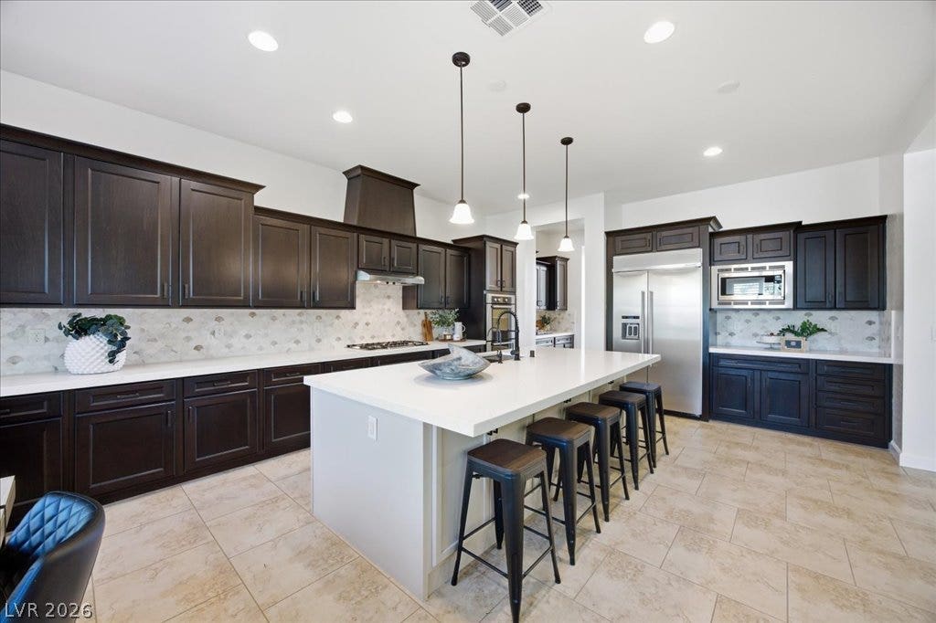 8030 Palm Cove Court, Las Vegas, NV 89129 Rich dark cabinetry contrasts beautifully with white countertops and tile flooring in this modern kitchen.