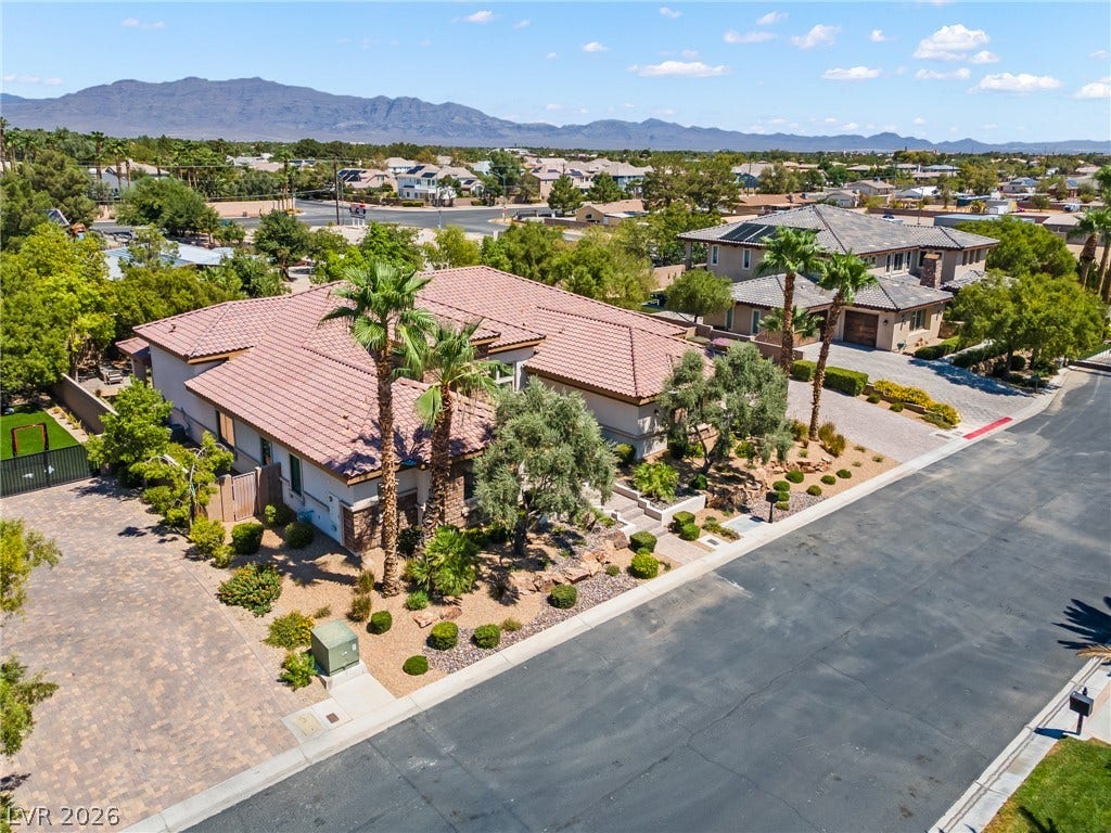 8030 Palm Cove Court, Las Vegas, NV 89129 An aerial perspective showcases a tiled-roof residence framed by desert landscaping and mountain backdrops.