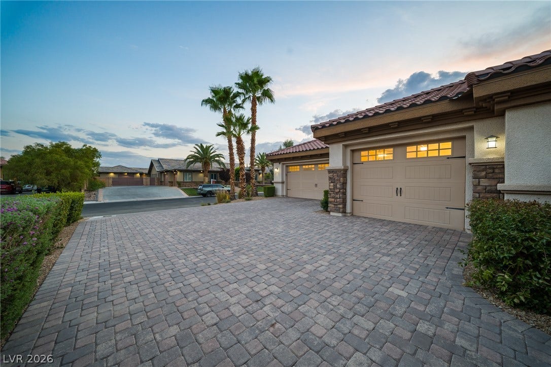 8030 Palm Cove Court, Las Vegas, NV 89129 An elegant paver driveway leads to the garage of this desert-style home under dramatic evening skies.