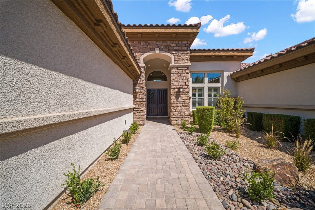 8030 Palm Cove Court, Las Vegas, NV 89129 A paved stone walkway leads directly to the stone-accented arched entryway of this desert home.