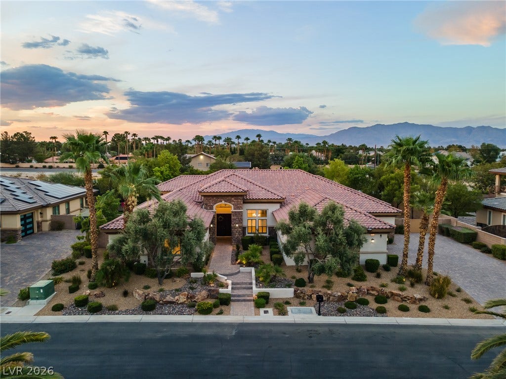 8030 Palm Cove Court, Las Vegas, NV 89129 Spanish tile roofing and professional desert landscaping frame this modern estate against mountain backdrops.