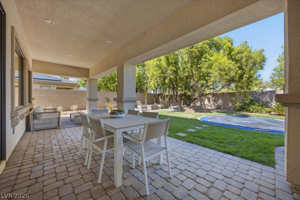 8030 Palm Cove Court, Las Vegas, NV 89129 An inviting covered patio featuring brick pavers opens directly onto a manicured green lawn.
