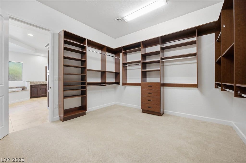 8030 Palm Cove Court, Las Vegas, NV 89129 Primary Custom built-in shelving and soft carpeting define this spacious closet space.
