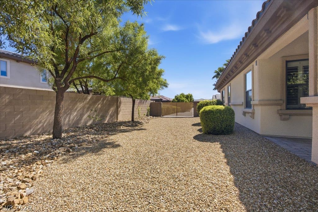 8030 Palm Cove Court, Las Vegas, NV 89129 Mature trees shade a low-maintenance gravel yard enclosed by a block wall and private gate.
