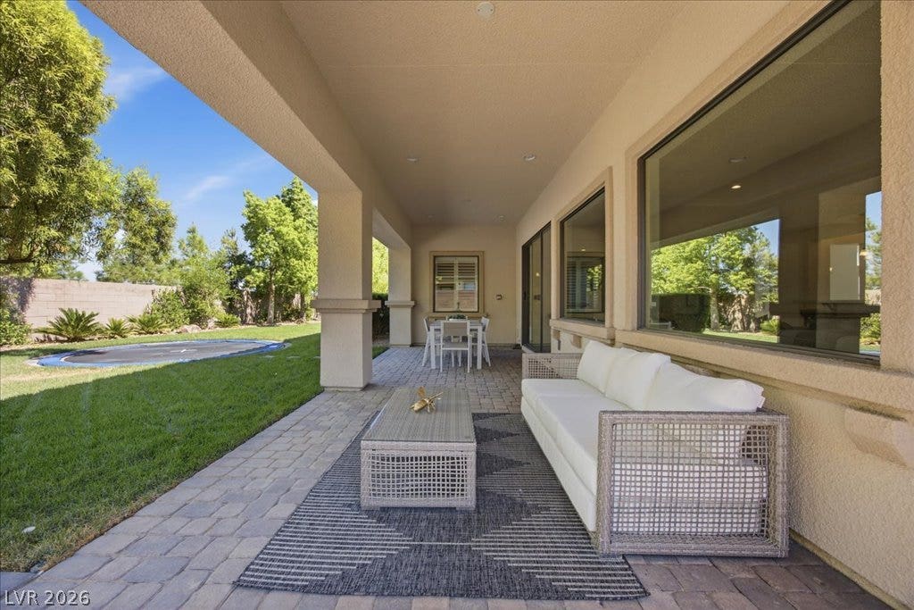 8030 Palm Cove Court, Las Vegas, NV 89129 An inviting covered patio features neat stone pavers alongside a manicured green lawn.