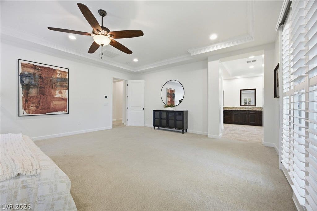 8030 Palm Cove Court, Las Vegas, NV 89129 An elegant tray ceiling with crown molding highlights this primary suite leading into a bathroom.