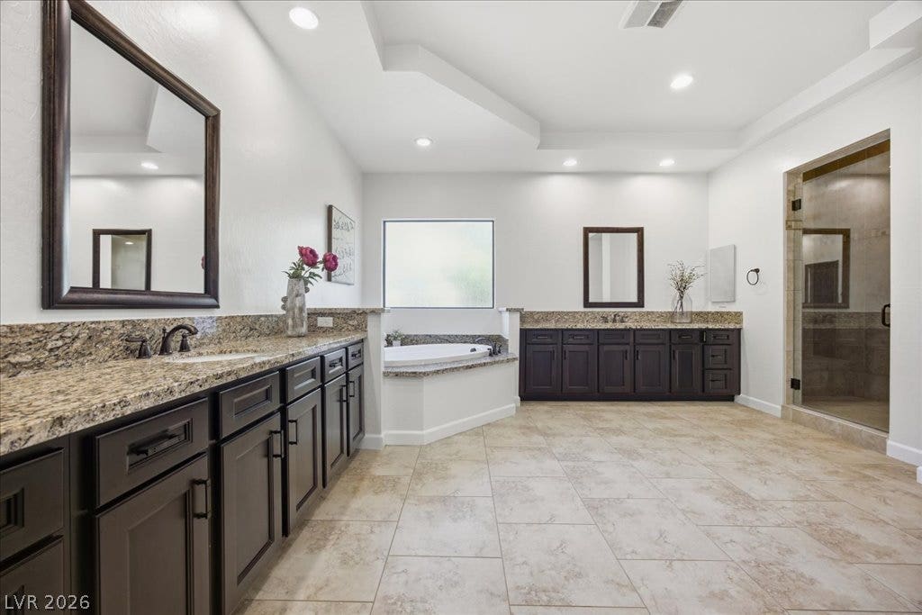 8030 Palm Cove Court, Las Vegas, NV 89129 A spacious bathroom features dual vanities, large tile flooring, and a corner soaking tub.