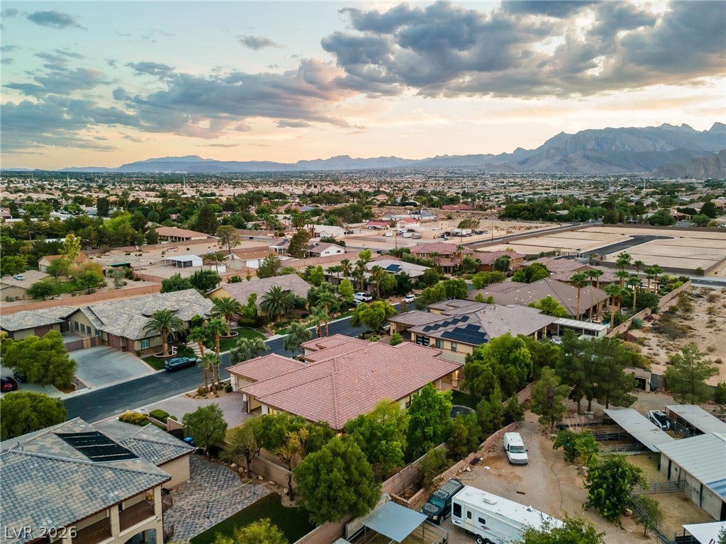 8030 Palm Cove Court, Las Vegas, NV 89129 Distant mountains frame a sprawling neighborhood under a dramatic western sunset sky.
