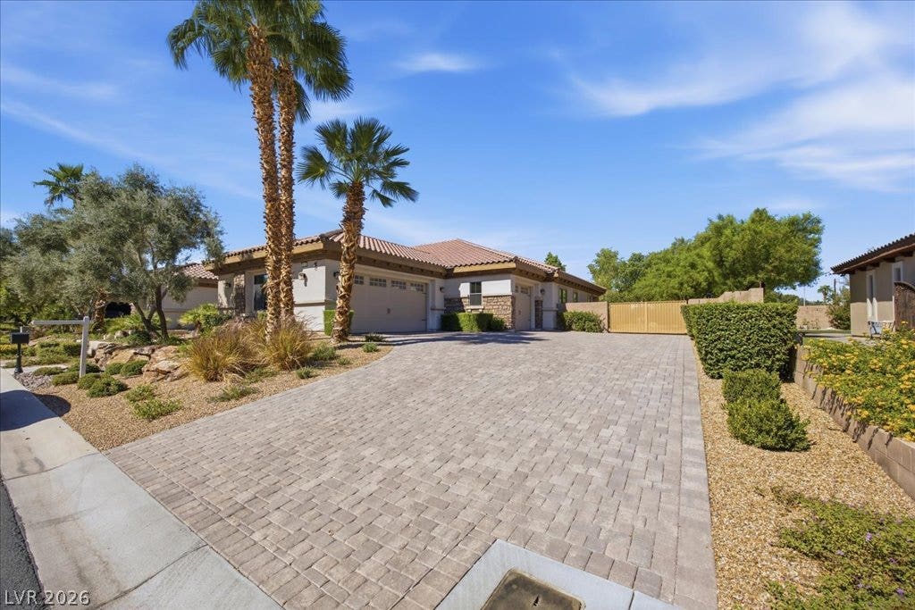 8030 Palm Cove Court, Las Vegas, NV 89129 An elegant paver driveway leads to a classic tile-roof residence framed by desert palms.