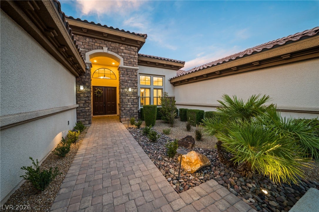8030 Palm Cove Court, Las Vegas, NV 89129 An inviting stone-accented entryway leads past manicured desert landscaping along a paved walkway.