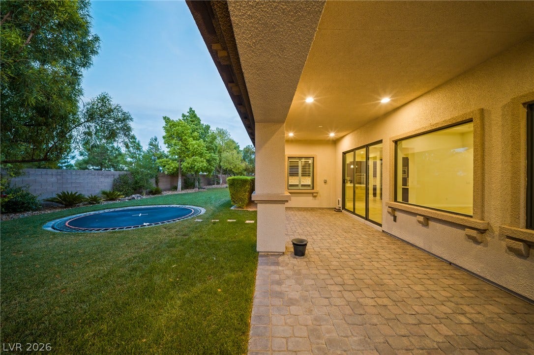 8030 Palm Cove Court, Las Vegas, NV 89129 An expansive covered patio crafted with interlocking pavers overlooks a manicured green lawn.