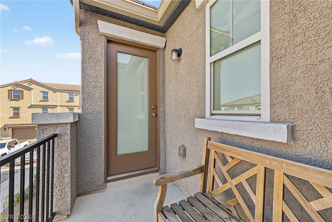 1180 Gypsum Hills Court, Henderson, NV 89002 A private upper-level balcony features stucco walls, concrete flooring, and a glass-paneled door.
