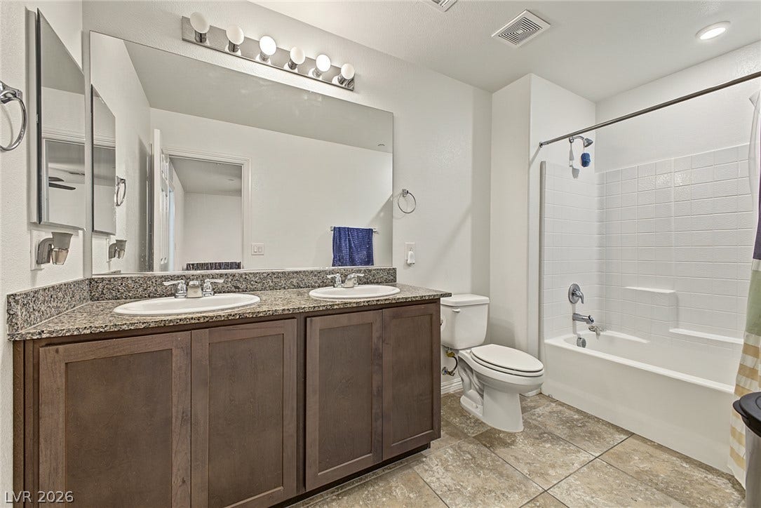 1180 Gypsum Hills Court, Henderson, NV 89002 Tiled flooring and a stone-countertop double vanity define this functional bathroom space.