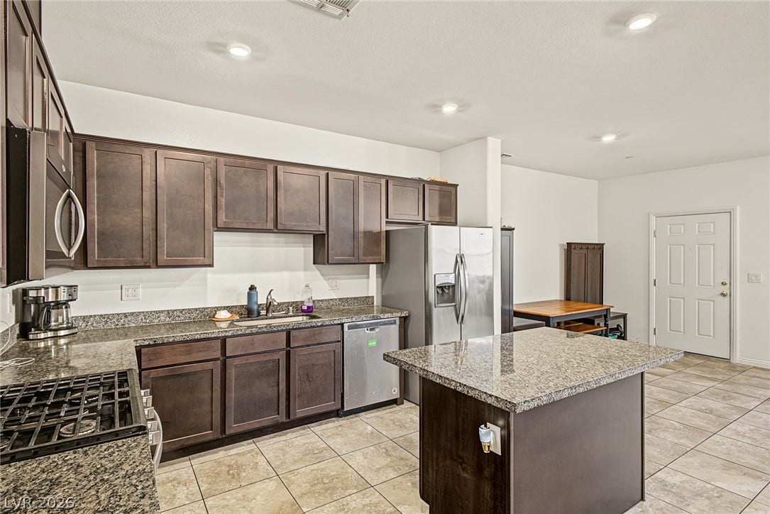 1180 Gypsum Hills Court, Henderson, NV 89002 Granite countertops and dark cabinetry define this functional kitchen with a central prep island.