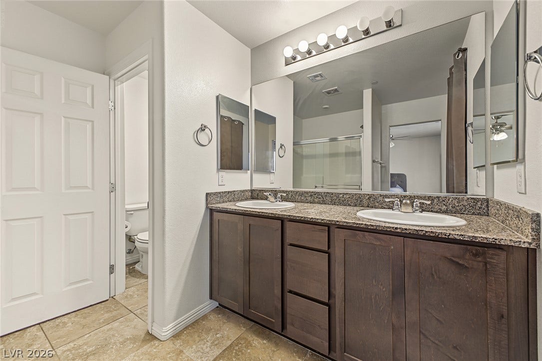 1180 Gypsum Hills Court, Henderson, NV 89002 A spacious vanity with dual sinks and stone countertops anchors this elegant bathroom space.