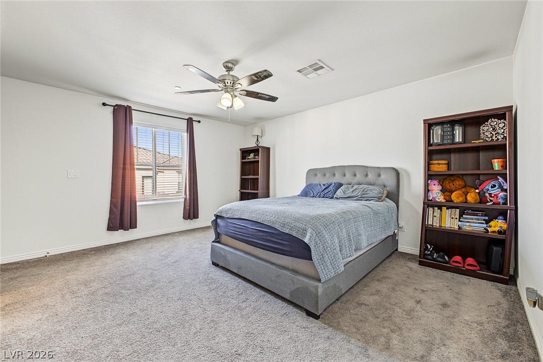 1180 Gypsum Hills Court, Henderson, NV 89002 A spacious bedroom features soft wall-to-wall carpeting and a wide window that invites natural light.