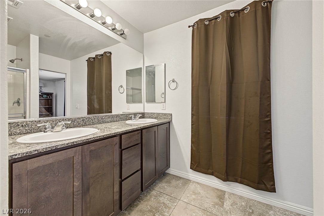 1180 Gypsum Hills Court, Henderson, NV 89002 A spacious double vanity with granite counters anchors this modern bathroom.