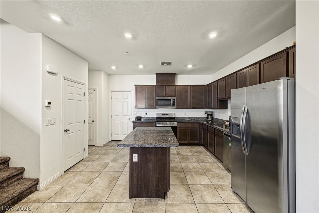 1180 Gypsum Hills Court, Henderson, NV 89002 Rich wood cabinetry and expansive granite countertops define this functional, open kitchen layout.