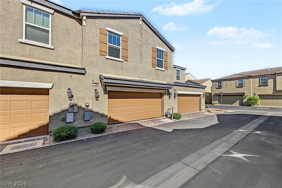 1180 Gypsum Hills Court, Henderson, NV 89002 Multi-level stucco townhome design integrates attached garage parking with paved driveways under clear blue skies.