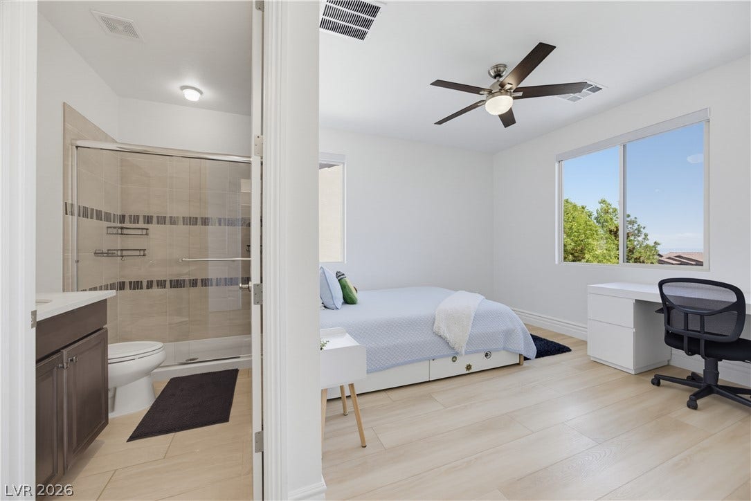 446 Bosco Di Fiore Street, Las Vegas, NV 89138 Light-filled bedroom suite features wood-look floors, tall windows, and an attached modern bathroom.