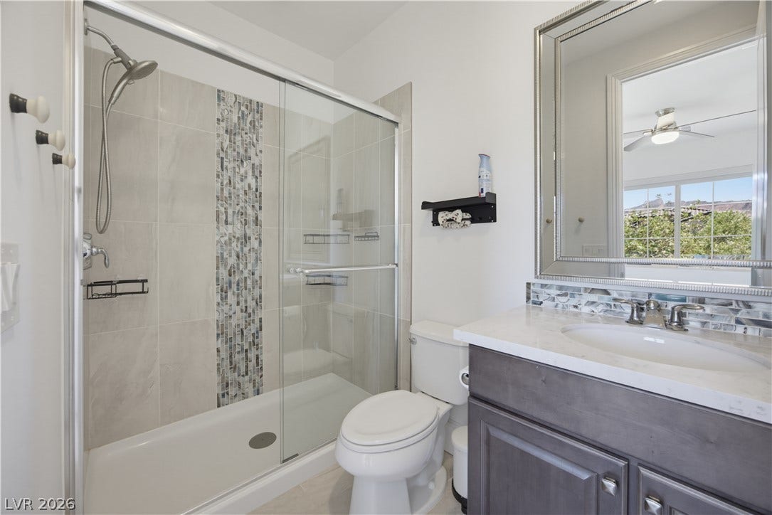 446 Bosco Di Fiore Street, Las Vegas, NV 89138 Clean lines and stone counters highlight this updated vanity area with a glass-enclosed shower.